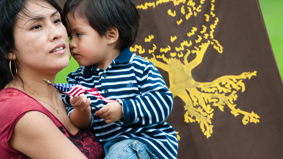 Photo of young immigrant mother holding on to her son