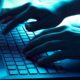 Photo of a hacker typing on a laptop