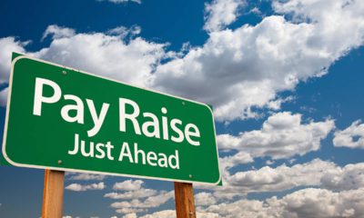 Composite image of a pay raise ahead sign and blue skies