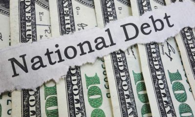 Photo of money and "national debt" on a ripped piece of paper