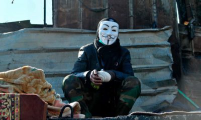 Photo of a protester wearing a Guy Fawkes mask