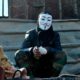 Photo of a protester wearing a Guy Fawkes mask