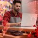 Composite image of a small businessman at laptop and COVID-19 symbols